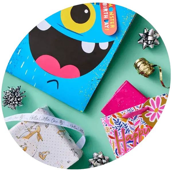 Colourful children's birthday card, gift bags, wrapping paper, ribbons, and presents arranged on a turquoise background.