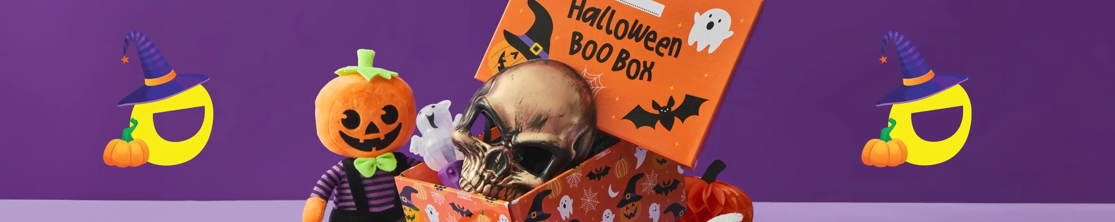 Halloween Boo Box filled with a metallic skull, ghost figure, and purple bat, surrounded by festive decorations including a plush pumpkin, glittery pumpkin, spider, rat, and ghost on a purple background. Halloween Boo Box filled with a metallic skull, ghost figure, and purple bat, surrounded by festive decorations including a plush pumpkin, glittery pumpkin, spider, rat, and ghost on a purple background.